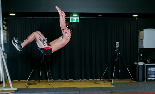 Man in mid-air doing a backflip in the performance lab.