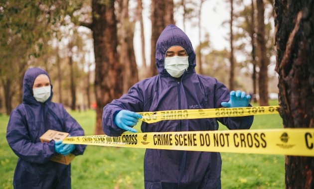 Man and women marking out a crime scene with police tape