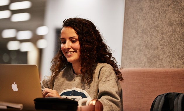 一个女学生在默多克图书馆用笔记本电脑工作.