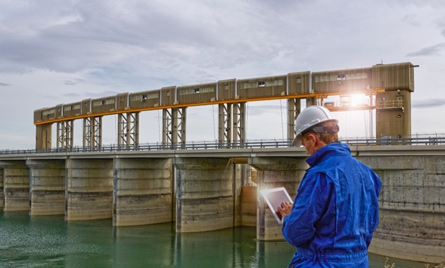 一名穿着反光背心的测量员在大坝上测量水.