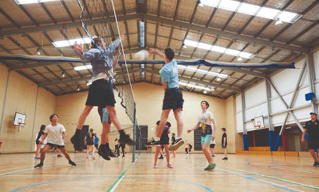 人们在打排球 on an indoor court.