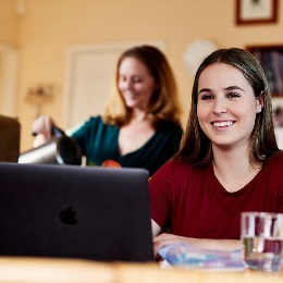 Woman with laptop and another woman making coffee