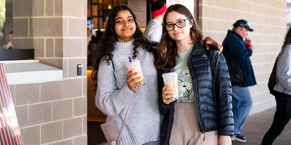 2 students with bubble tea outside Student Hub