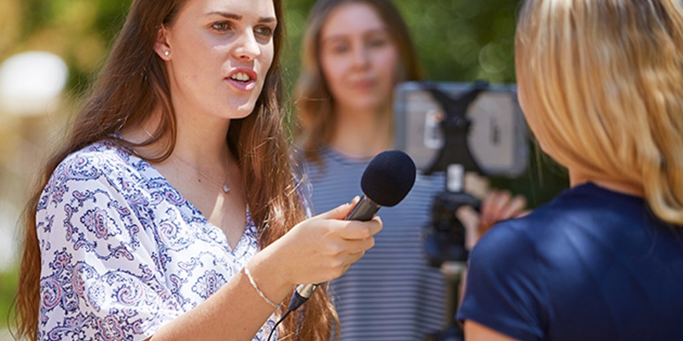 Female reporter with microphone, speaking to interviewee