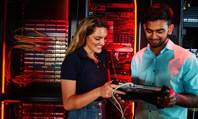 Female and male student working on a device in the IT server room.