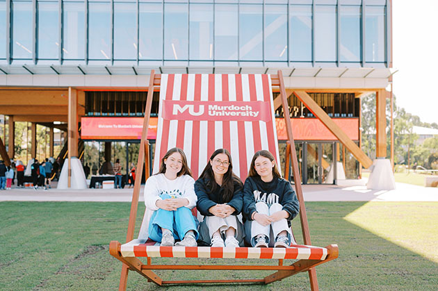 3 young students on oversized chair