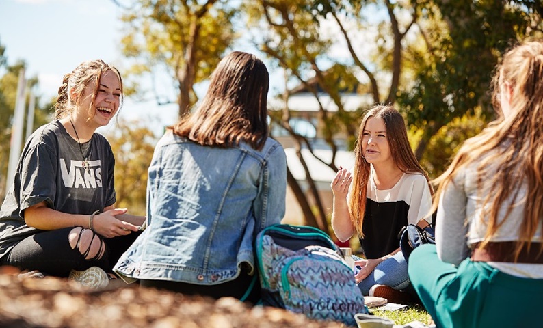 A group of students sitting and laughing together on Bush Court.
