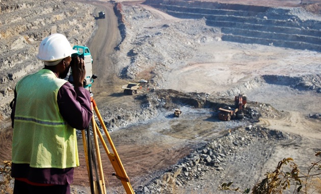 A locally employed surveyor surveying an open-pit copper mine in Zambia.