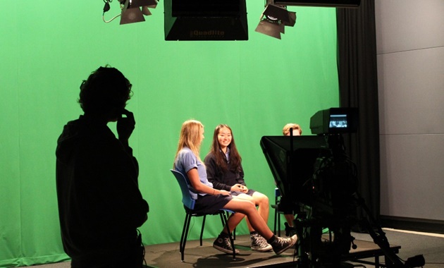 High school students against a green screen in a filming studio.