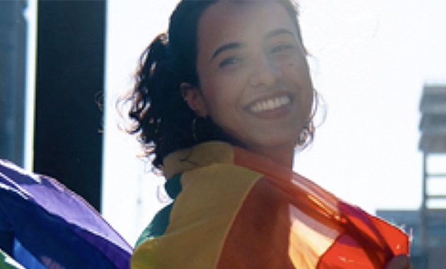 Woman with rainbow flag draped across shoulders
