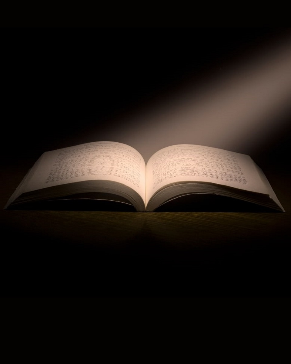 images of an open book on a dark background with a stream of light hitting the open pages