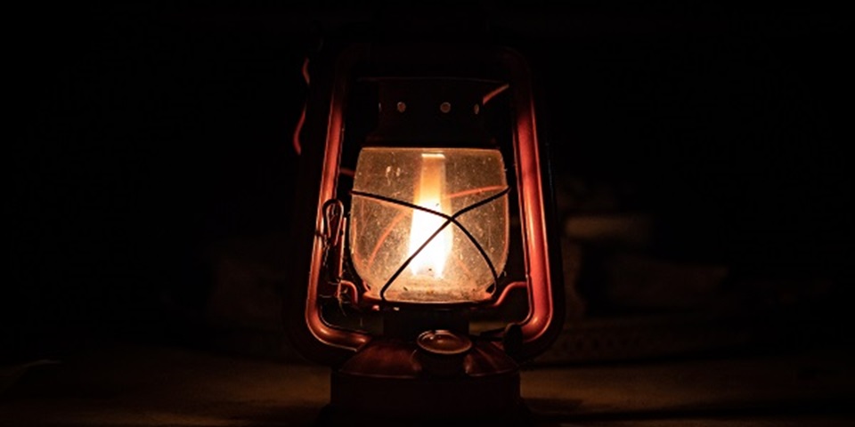 A lit gas lantern against a dark background