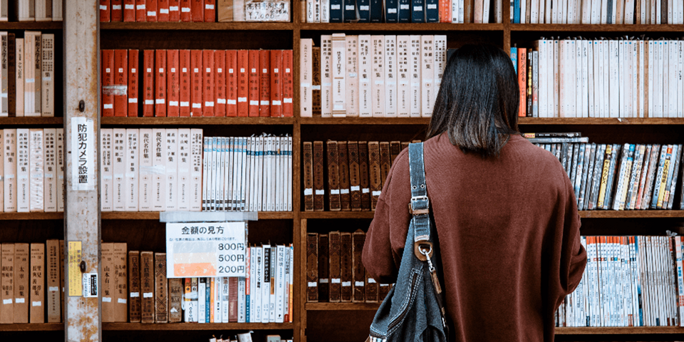 Person with back to camera browsing library shelves