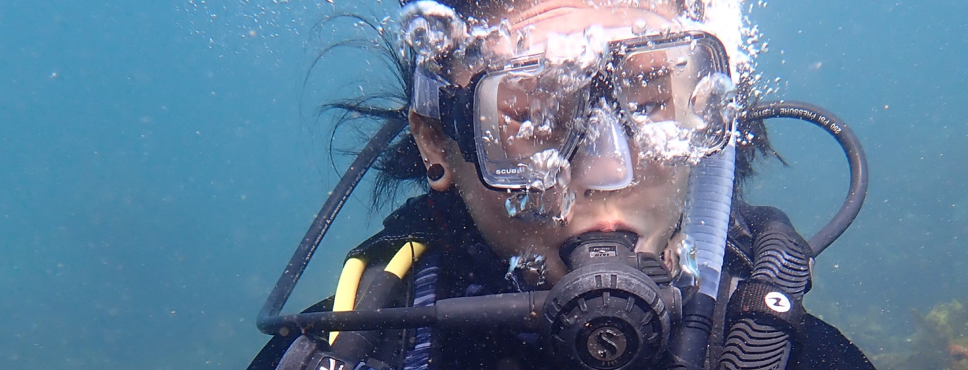 Scuba diving female blowing underwater bubbles