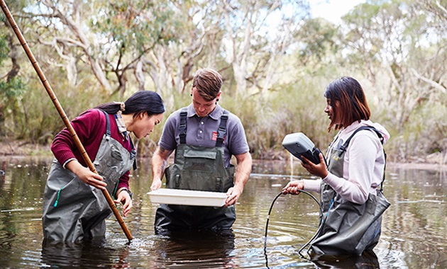 Three students experimenting in a lake.