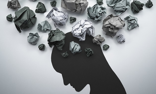 Silhouette of head looking down with scrunched up paper resembling thoughts