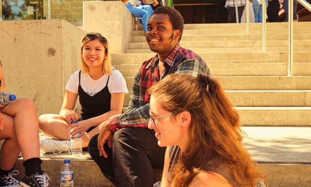 Group of students sitting on steps smiling and having fun