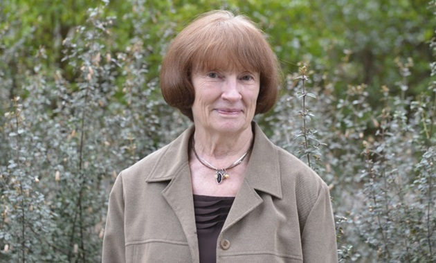 Janet Bornman smiling next to bushes