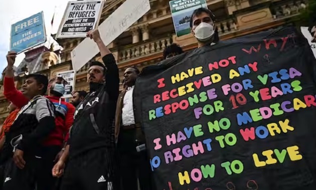 Refugee protestors holding signs that demand action for visas