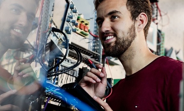 Student smiles and inspects electrical switchboard