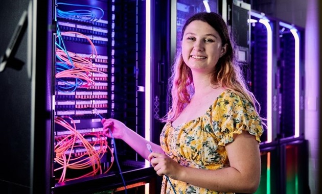 Murdoch Uni Student in information technology data centre smiles to camera