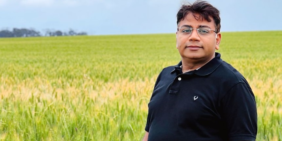 Professor Rajeev Varshney stands in field.