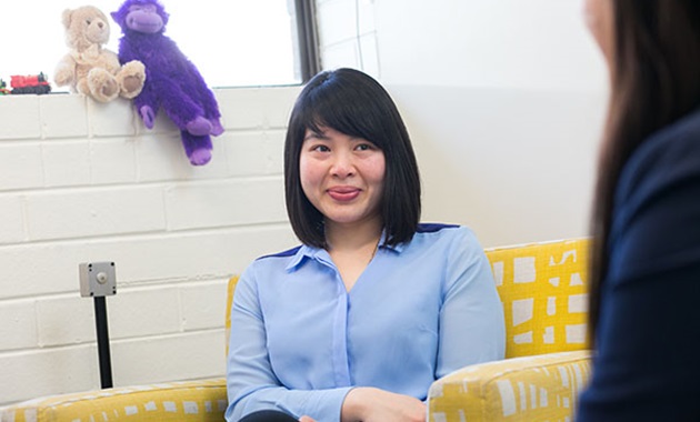 Female student sitting in armchair smiling.