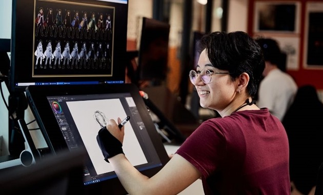 Student smiles and designs character on computer screen