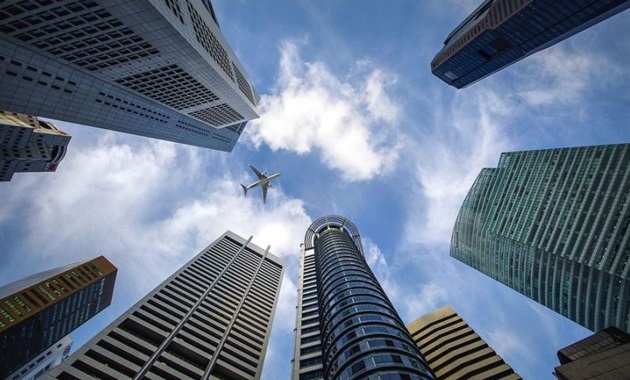 A plane flying over buildings in Singapore