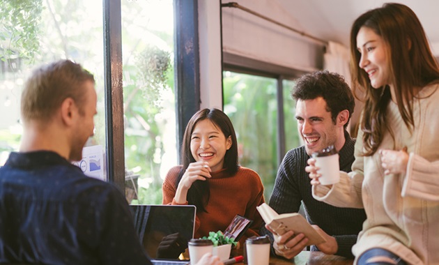 Group of students sitting around table with laptop, notebook and coffee