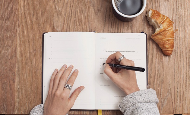 Top view of person writing in diary at desk