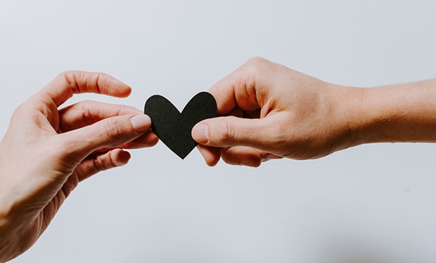 Two hands holding paper heart