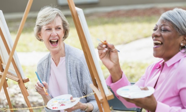 Two senior women laughing and painting